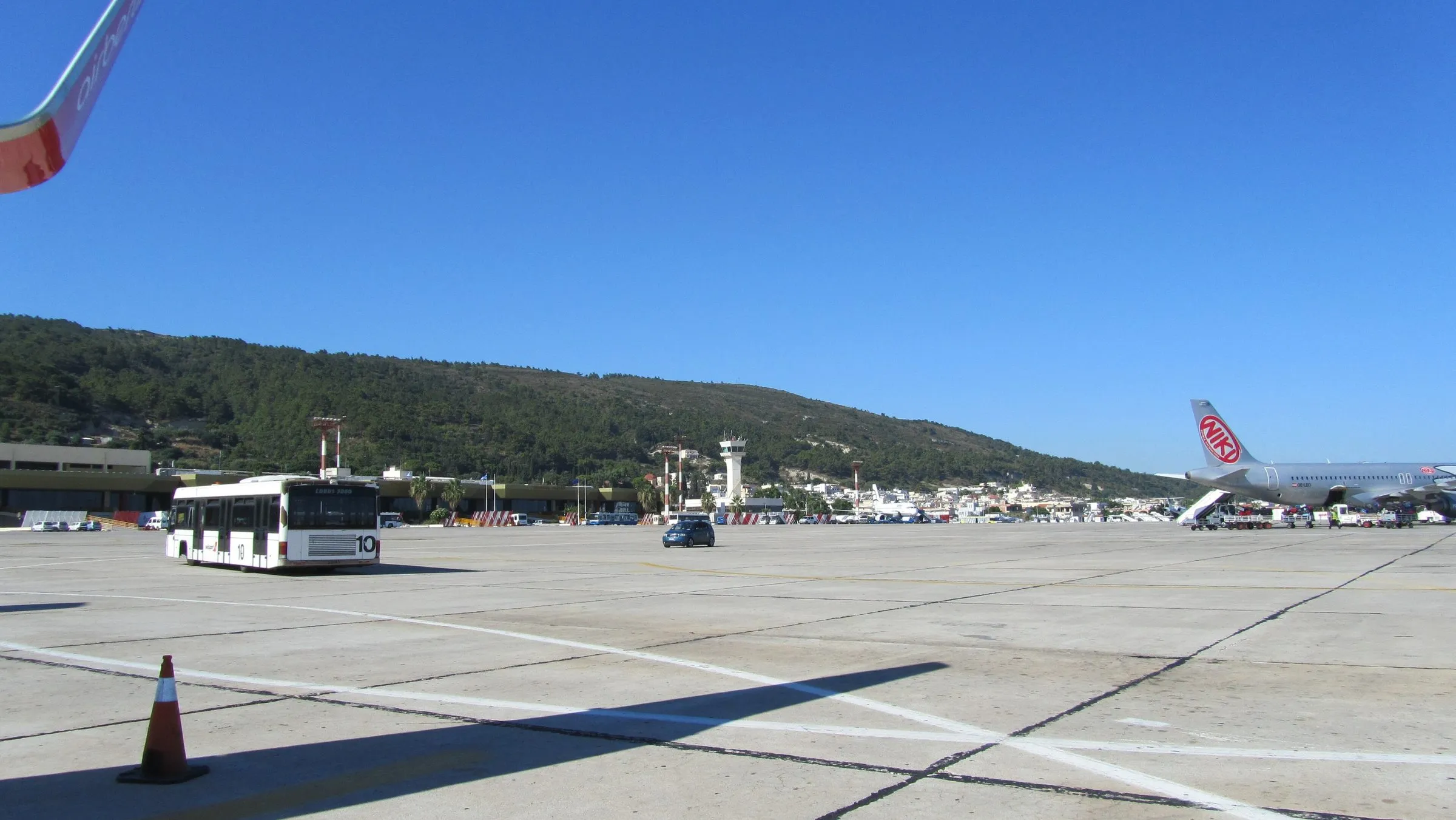 Vorfeld des Flughafens Rhodos Diagoras mit Flugzeug, Bus und Bergkulisse im Hintergrund
